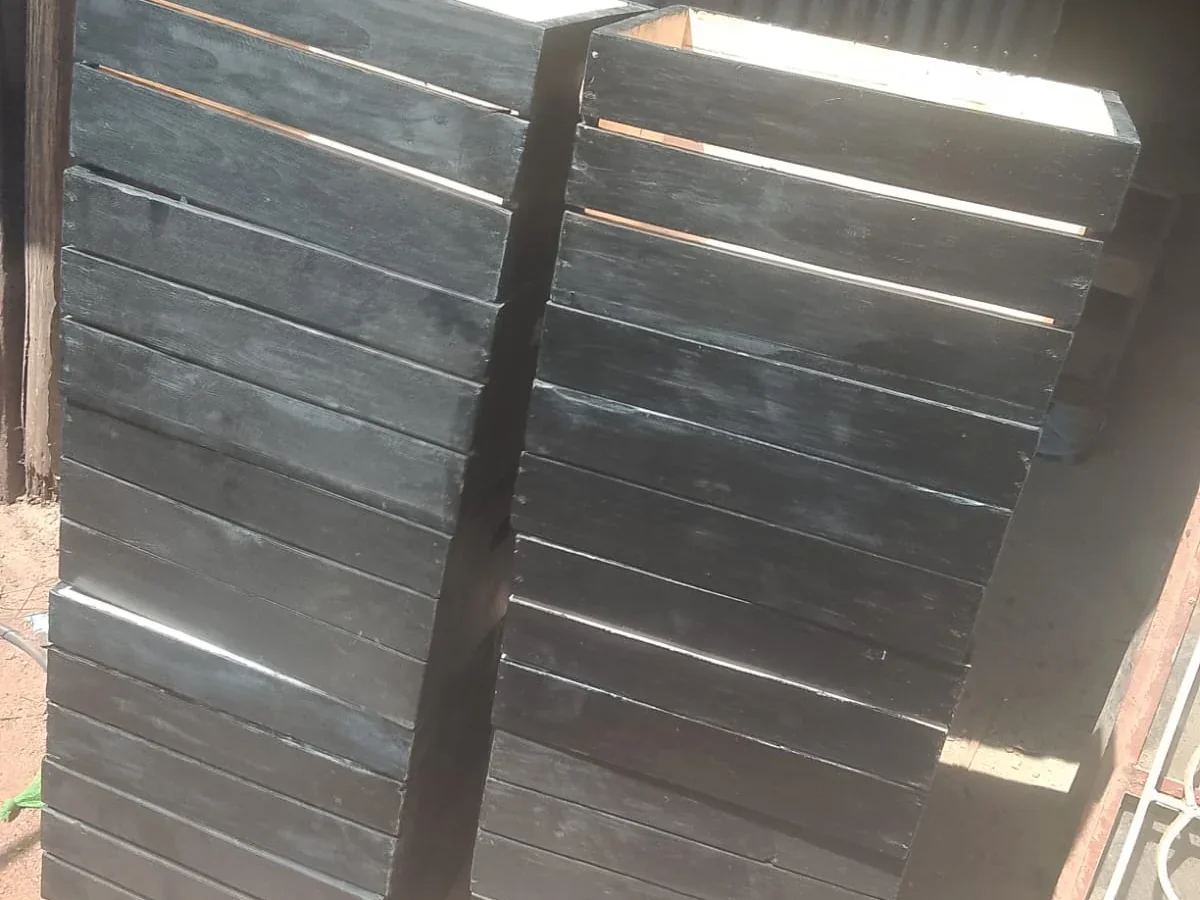 Two columns of charred black slatted wooden crates stacked at the Kangundo workshop