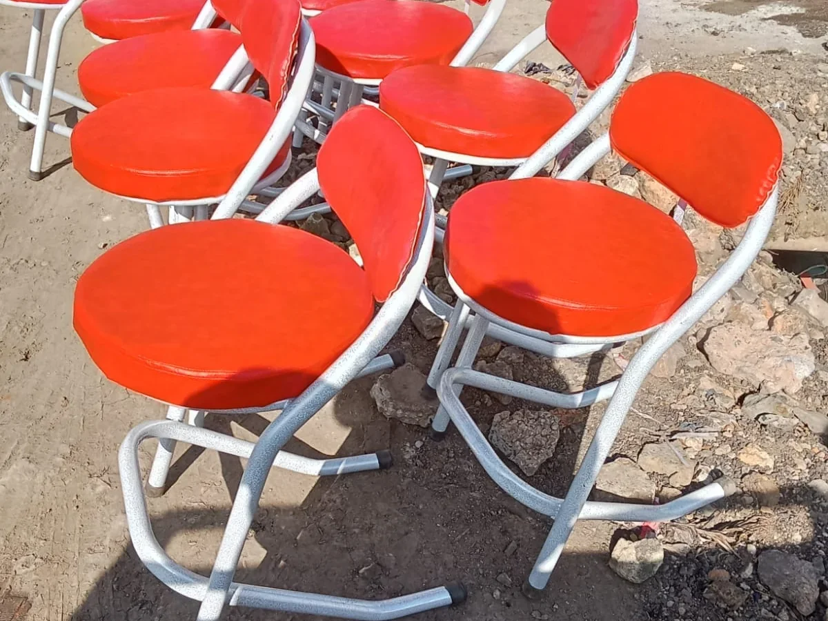 Red vinyl folding chairs with silver Z-frames displayed at a roadside stall.