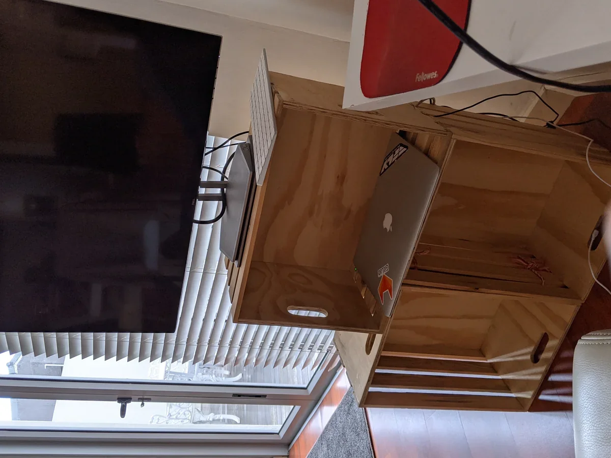 Modular standing workstation assembled entirely from stacked pine wooden crates with laptop, display monitor and keyboard.
