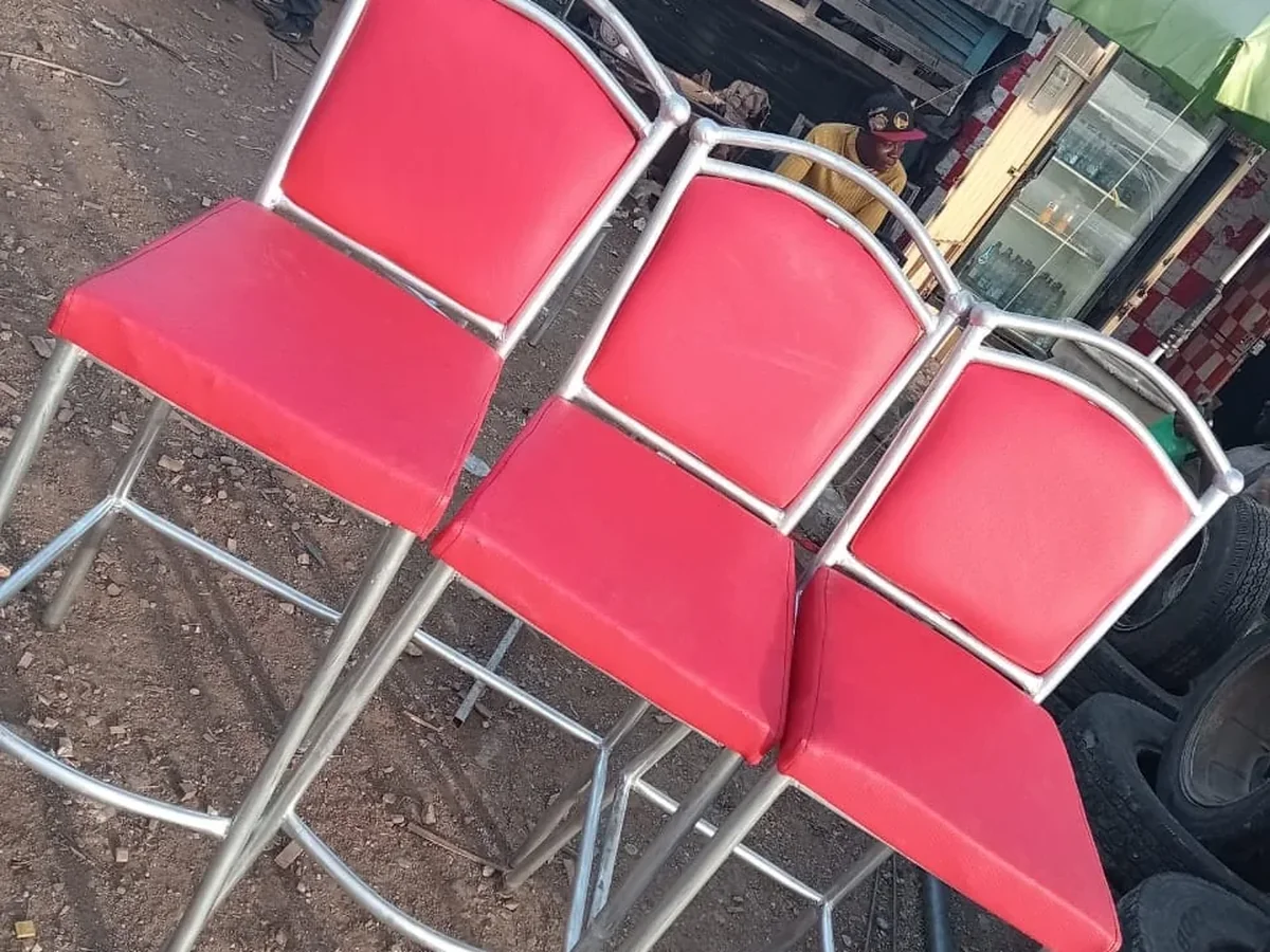Three-seat red vinyl waiting bench with a silver steel frame at a roadside market.